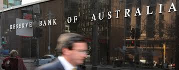 A blurred pedestrian walks past the Reserve Bank of Australia building, showcasing the bank's prominent signage.